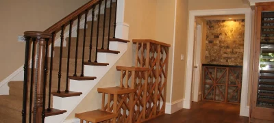 A custom-built wooden wine rack, for future display of collection of wine bottles, cleverly utilizes the often-unused under-stair space in a residential hallway, transforming it into a charming and functional wine cellar.