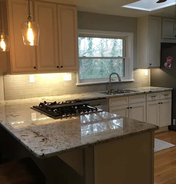 A kitchen with stainless steel appliances, including a stove, sink, and refrigerator. There are also brown cabinets and granite countertops.